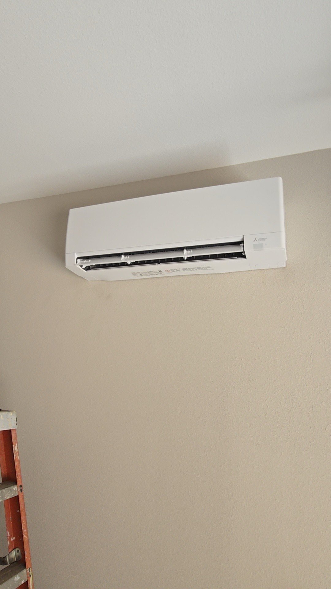 Wall-mounted mini-split HVAC indoor unit installed on a beige wall, highlighting a clean and efficient heating and cooling setup.