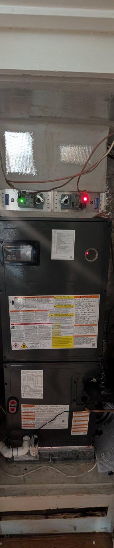 New residential HVAC air handler unit installation in a utility closet with visible ductwork and warning labels.