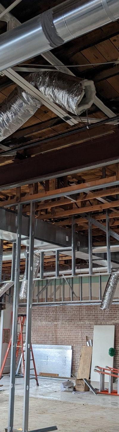 HVAC ductwork installation with rigid and flexible ducts in a commercial building under construction.