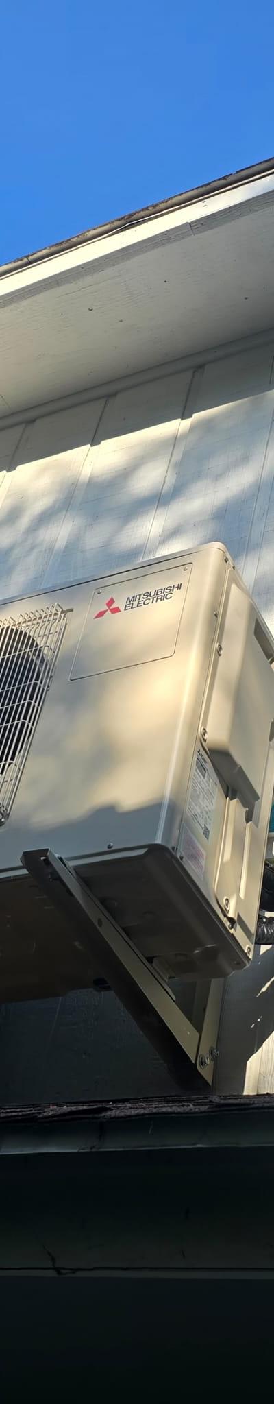 Mitsubishi Electric mini-split condenser on wall bracket with line hide on residential exterior.