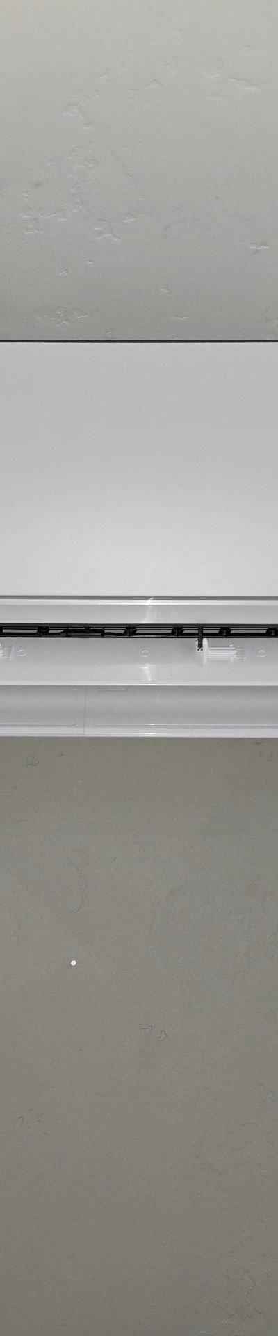 Mitsubishi Electric ductless mini-split indoor unit installed on a light grey wall with exposed conduit.
