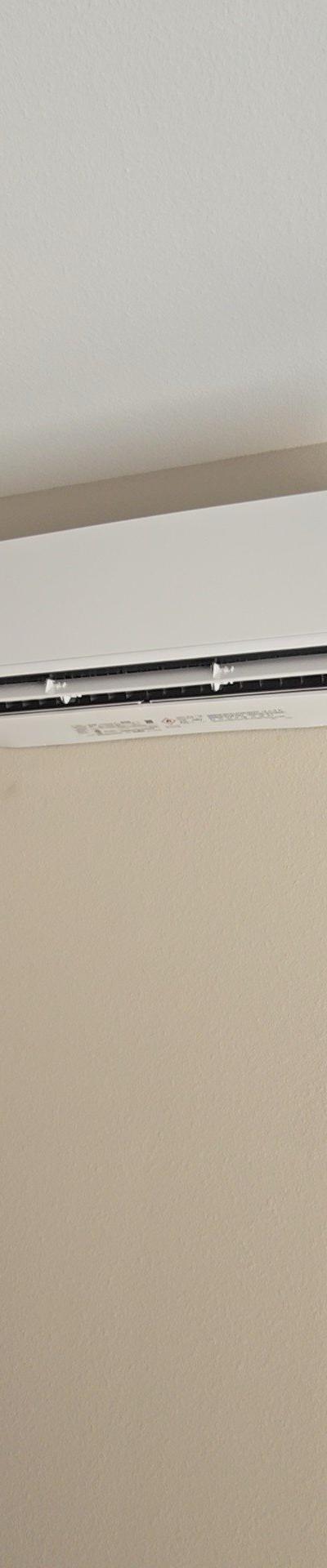 Wall-mounted mini-split HVAC indoor unit installed on a beige wall, highlighting a clean and efficient heating and cooling setup.