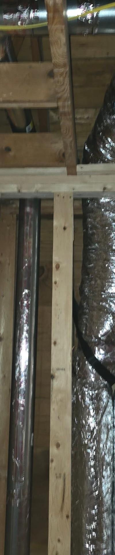 HVAC flexible and rigid ductwork installation within wooden framing during building construction.