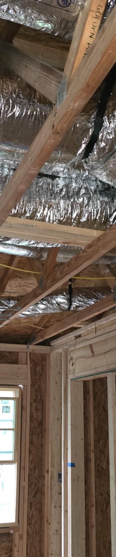 HVAC ductwork installation in a residential attic with insulated flexible ducts among wooden joists.